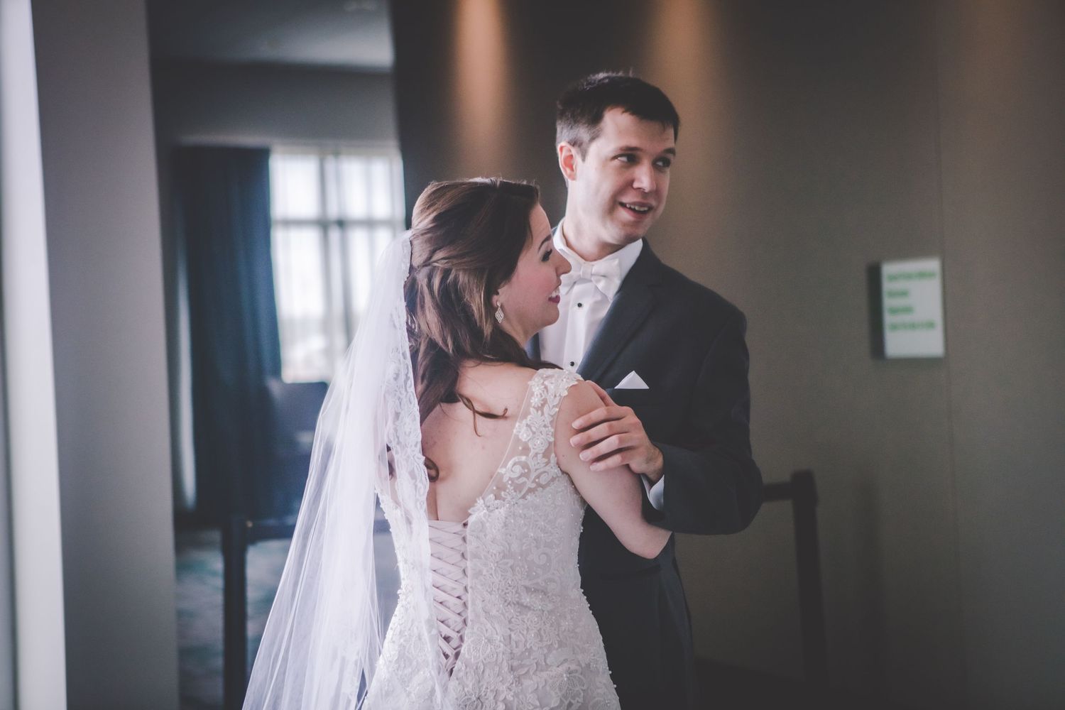 A joyful candid moment between newlyweds in a modern venue hallway.