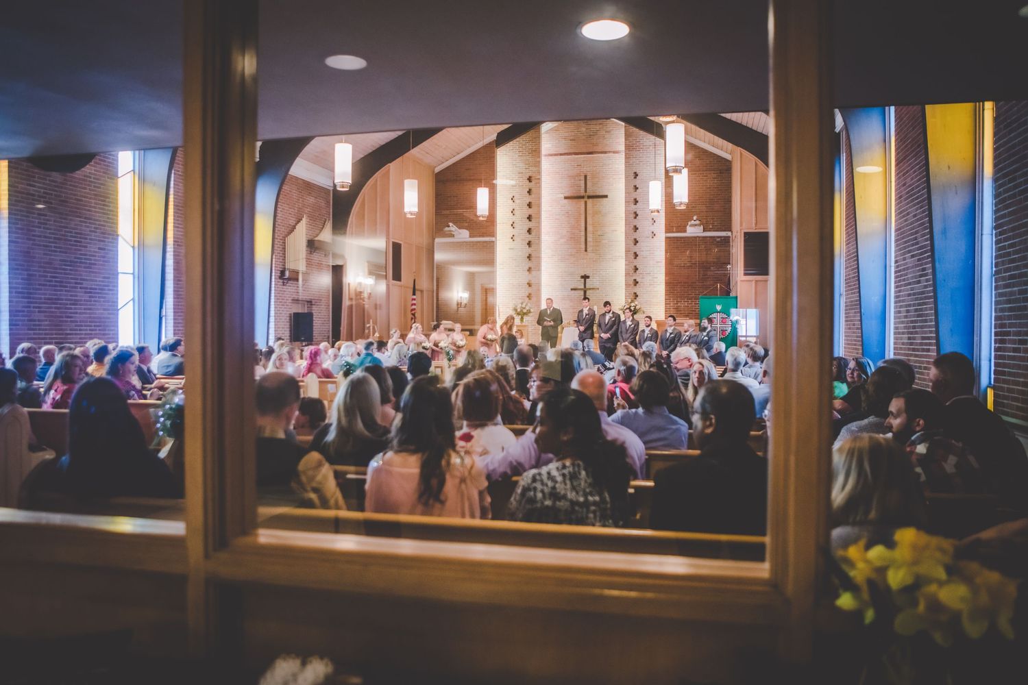 Wedding reception venue with warm lighting and guests seated at multiple tables.