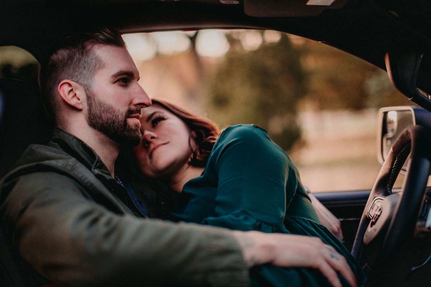 Loving couple embraces in car front seat with warm lighting creating cozy atmosphere.