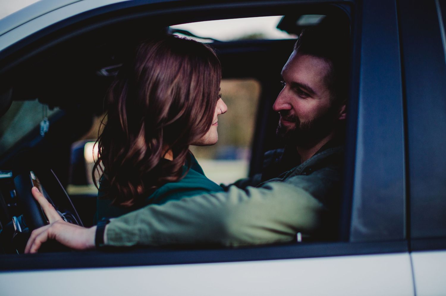 Couple sharing tender moment inside car with natural lighting.