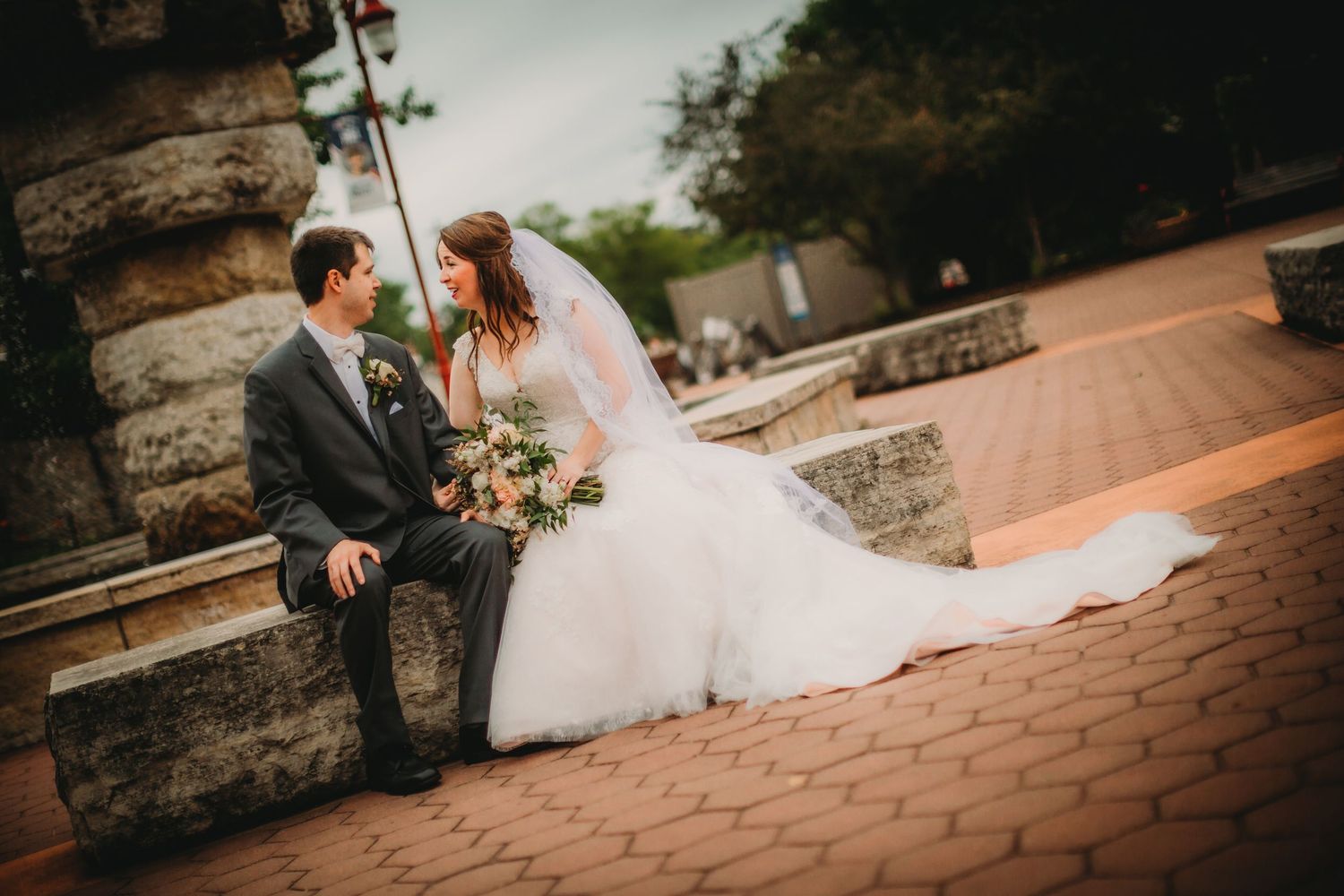 Wedding couple poses on brick pavers during outdoor photo session.