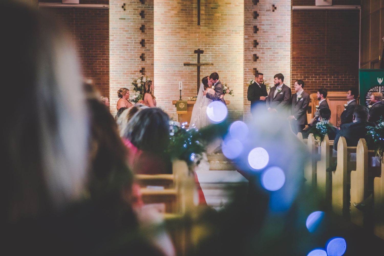 Church wedding ceremony with blue bokeh lights and wooden pews.