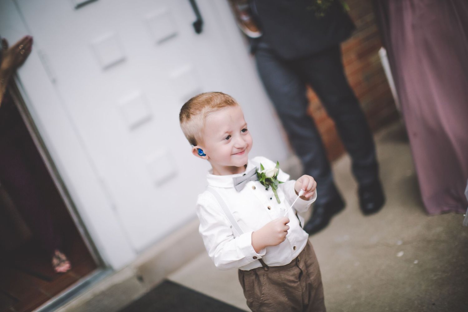 Small child in formal attire playing with confetti during wedding celebration.