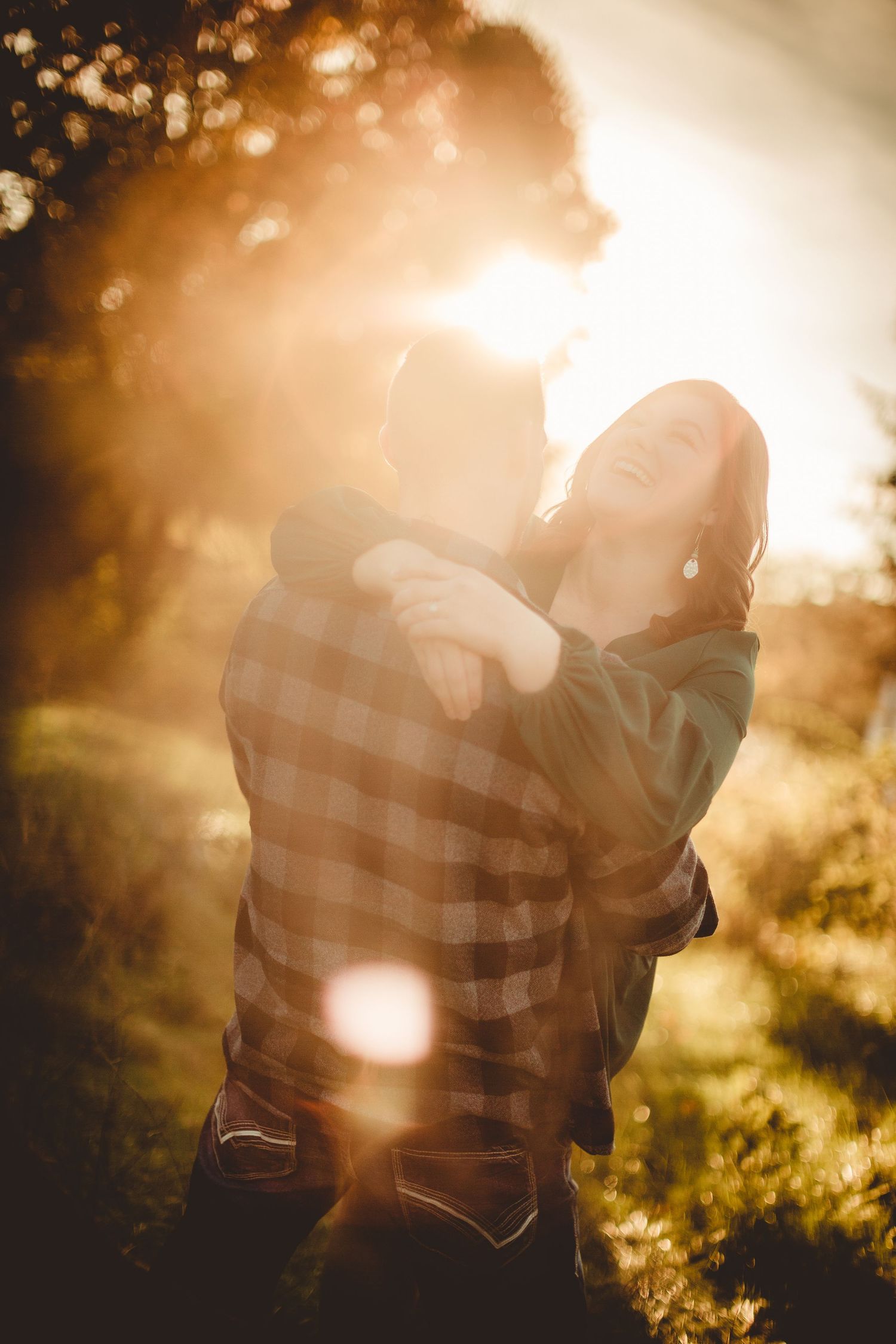 Silhouettes of a couple in an intimate embrace with dreamy golden sunlight bokeh.