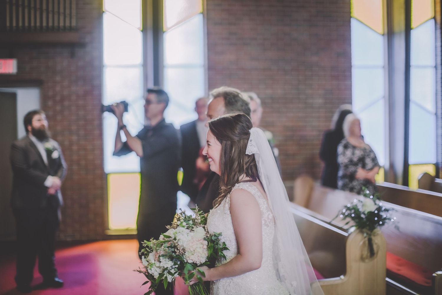 Wedding ceremony in progress inside brick-walled church with natural lighting.