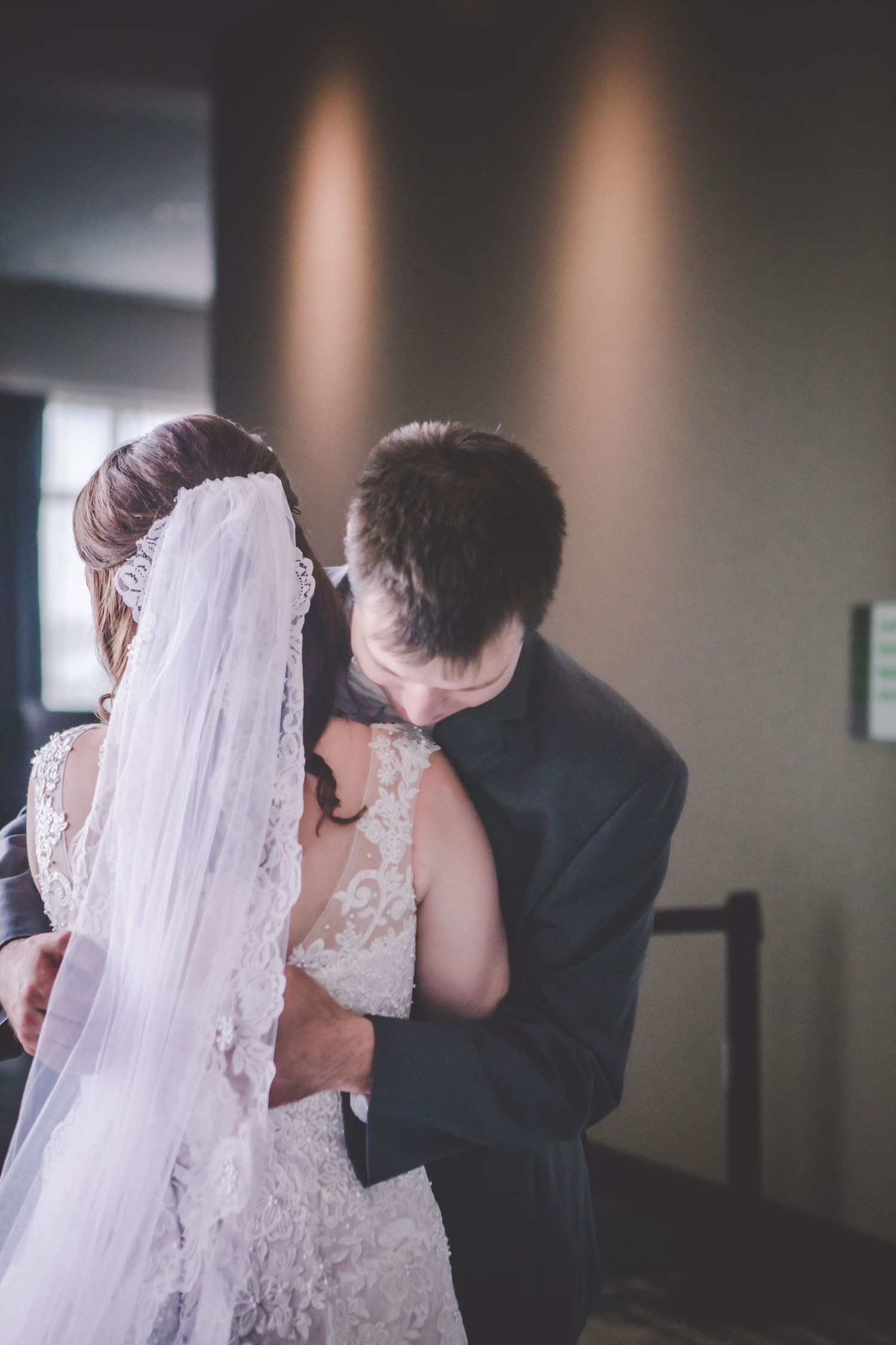 Intimate wedding moment captured in a softly lit corridor.