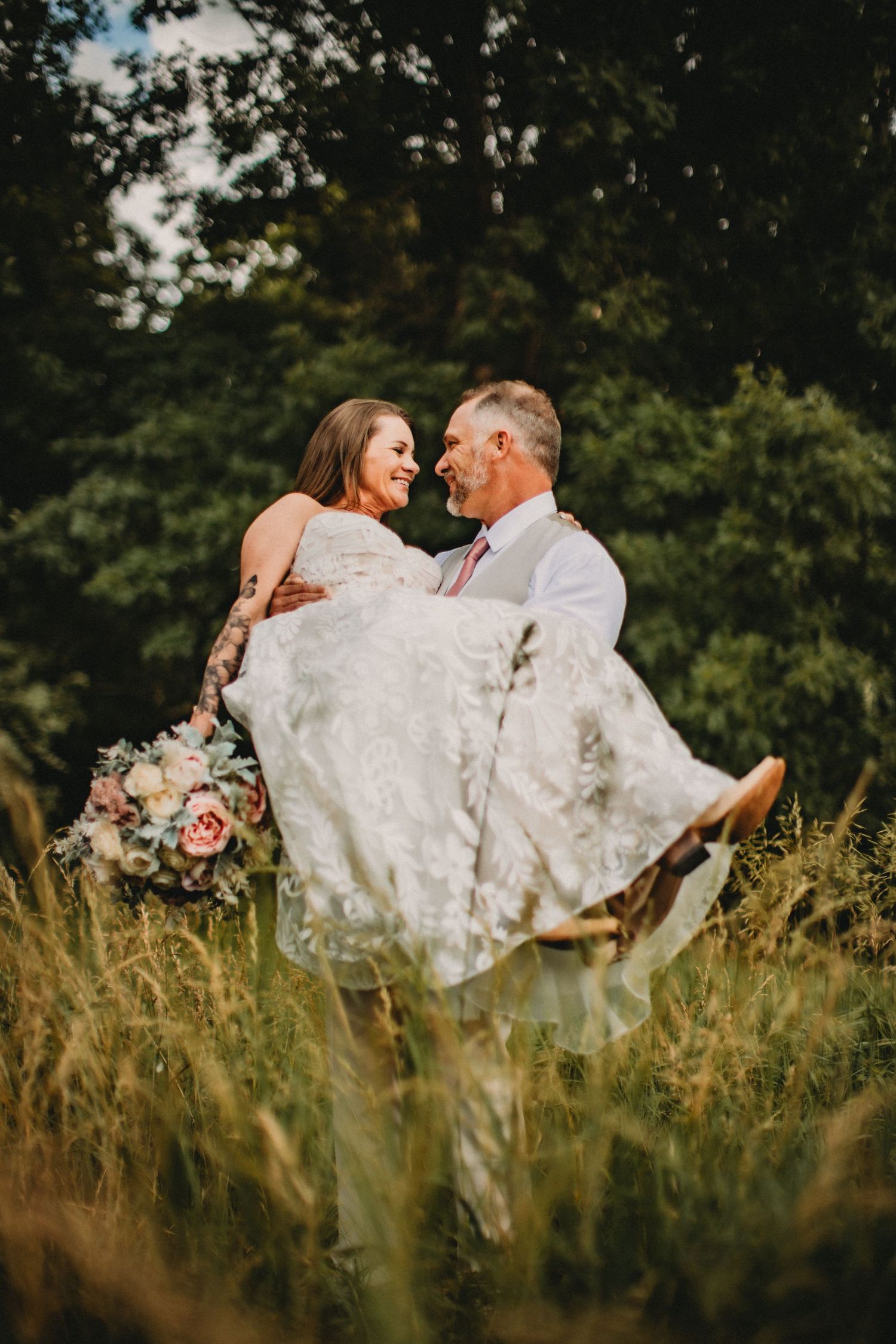 A romantic moment captured in a golden wheat field as a couple embraces in wedding attire.