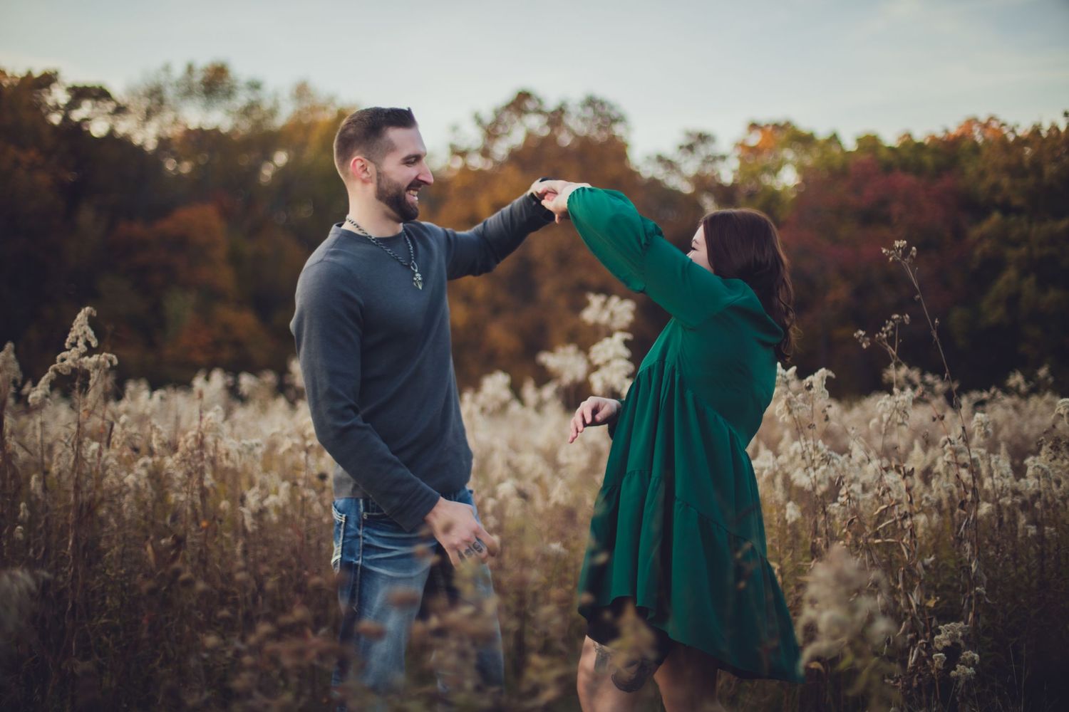 Happy couple sharing joyful moments together in a scenic autumn meadow.