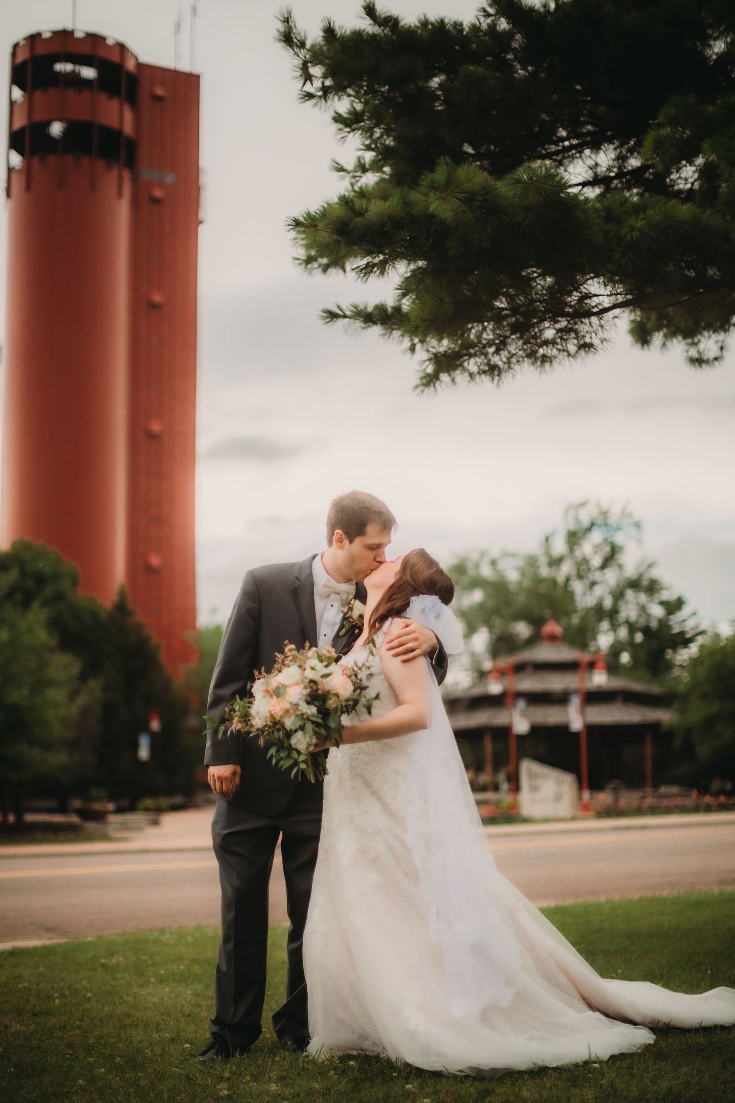 Romantic portrait of newlyweds sharing intimate moment by distinctive red tower.