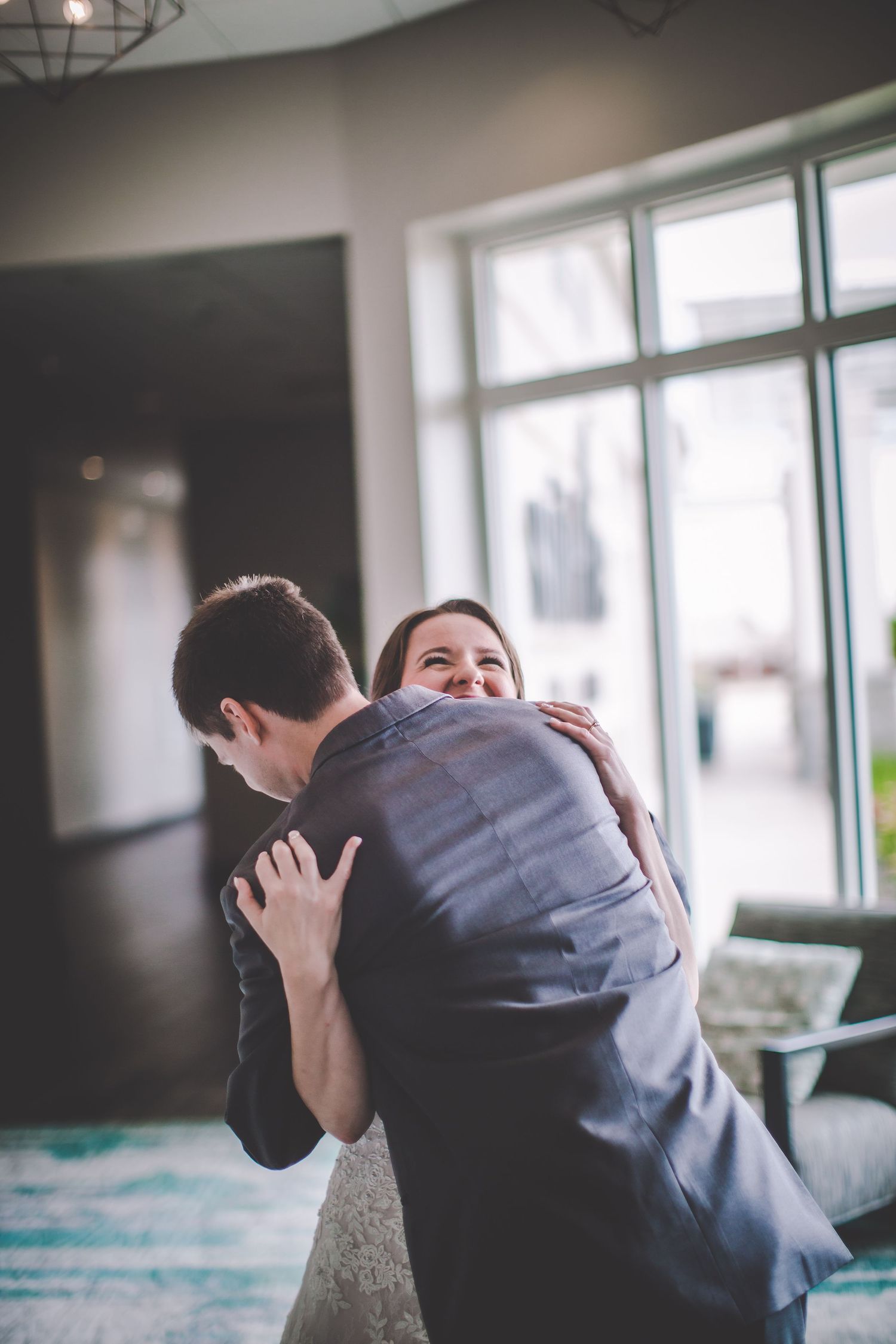 A couple shares an intimate embrace in a sunlit room during their first look at a wedding.