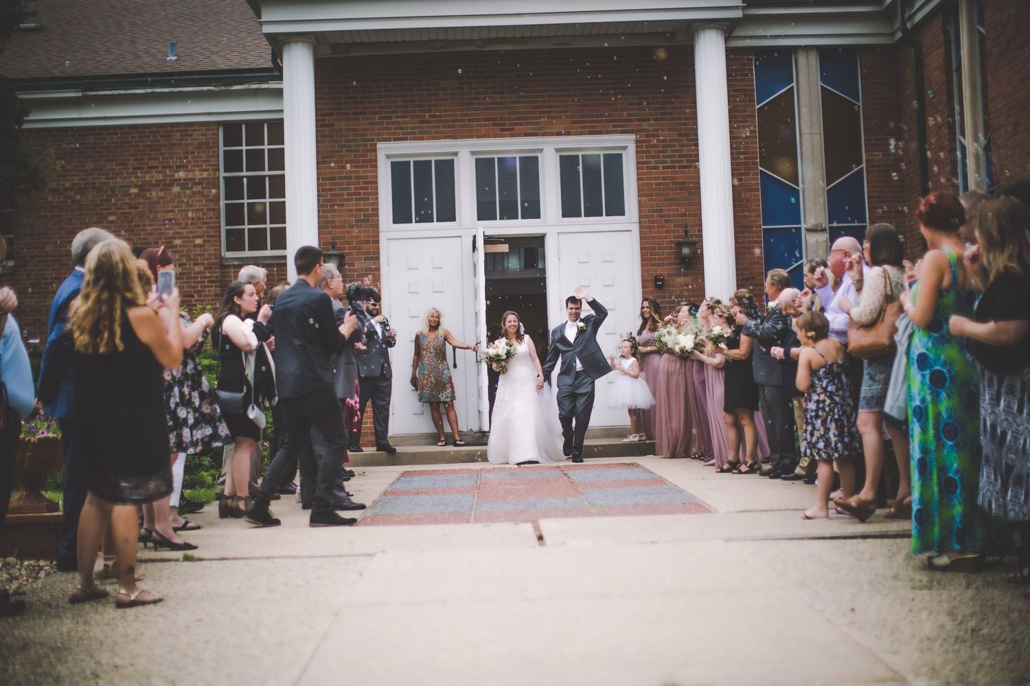 Guests gathered outside historic brick church building following wedding ceremony.
