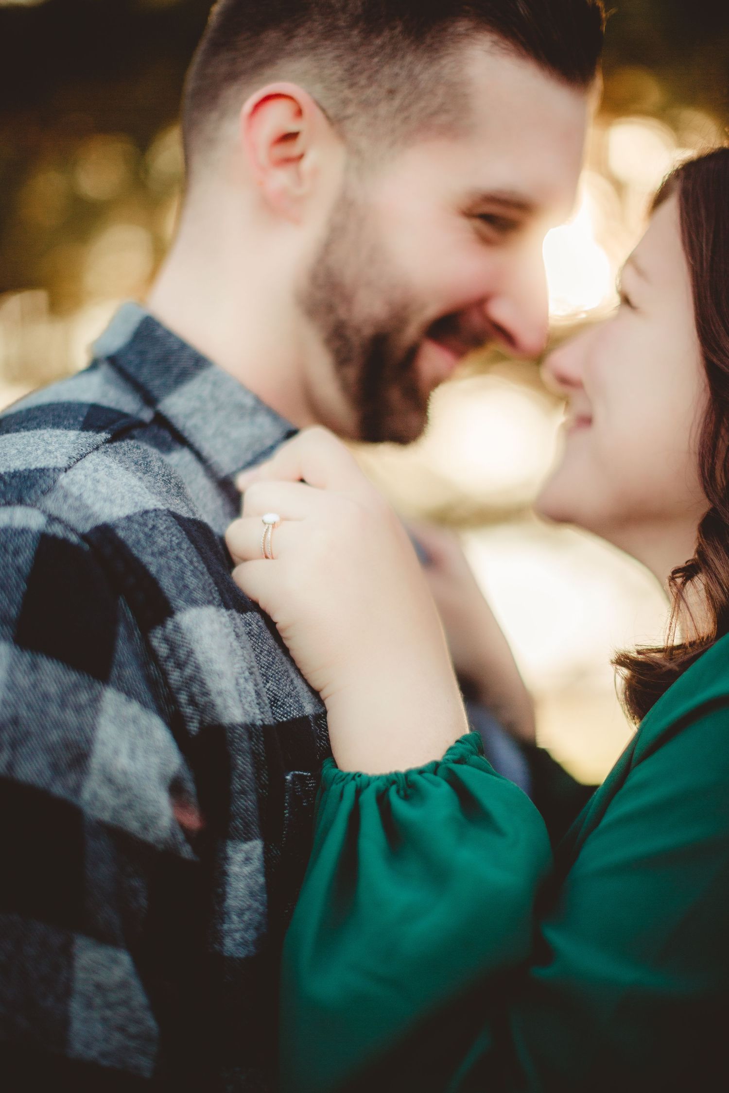 Intimate close-up of couple in plaid shirt and green dress during golden hour portrait session.