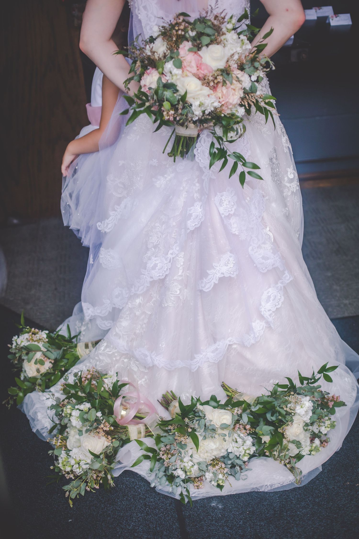 Wedding dress hem adorned with delicate pink and white floral arrangements.