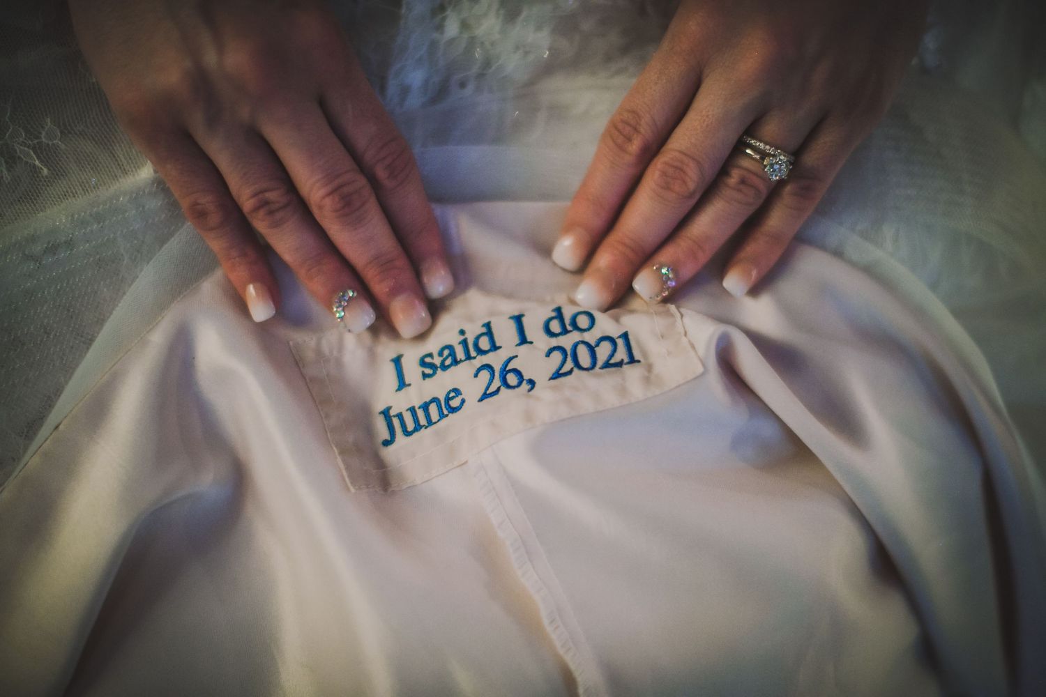 Detail shots of wedding dress embroidery showing blue text with date and message.