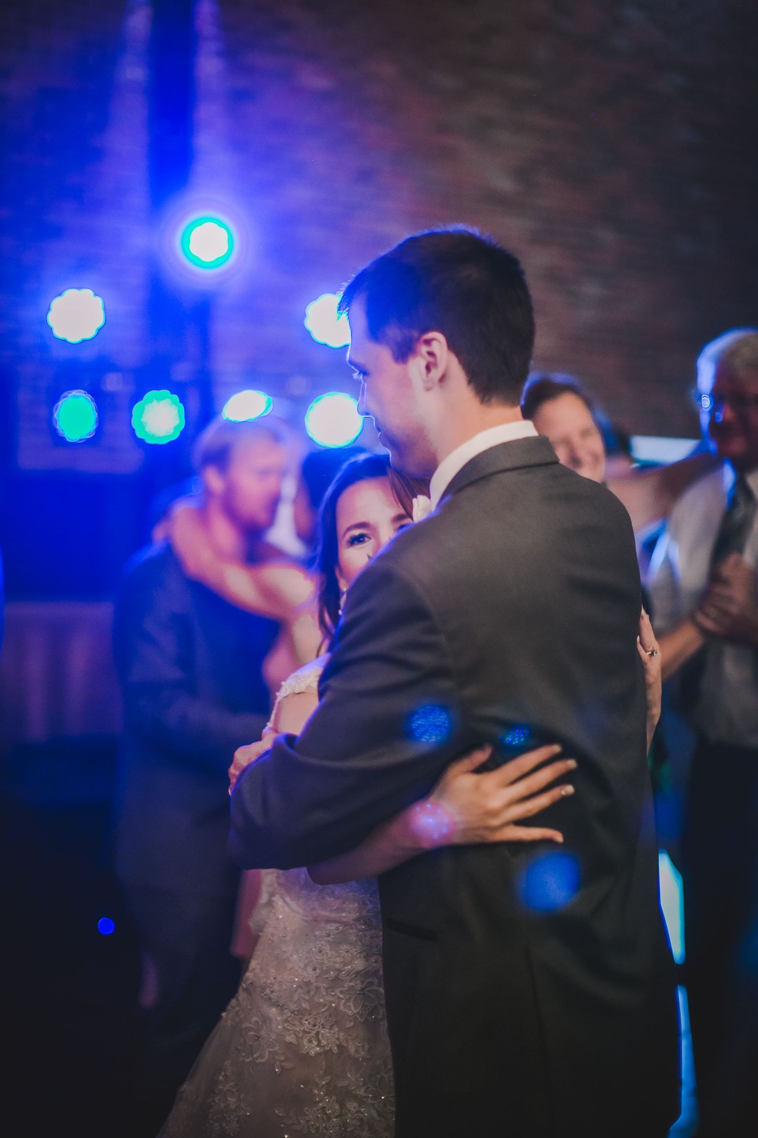A couple dances together under dramatic blue lighting at their wedding reception.