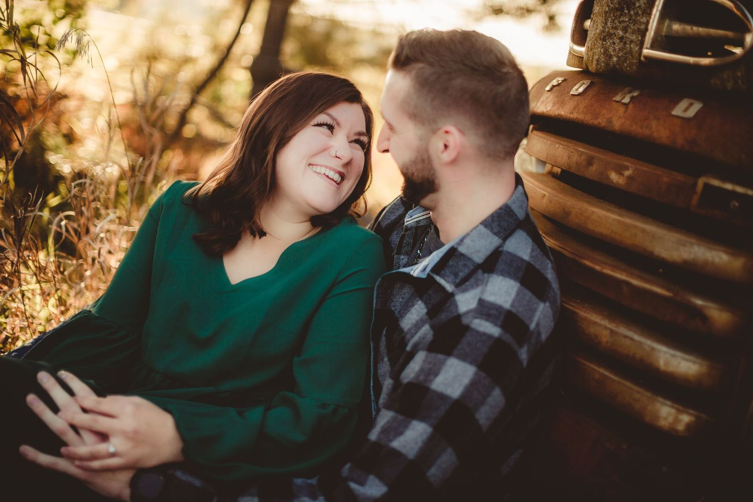 Couple in green sweater and plaid shirt share intimate moment by wooden cabin.