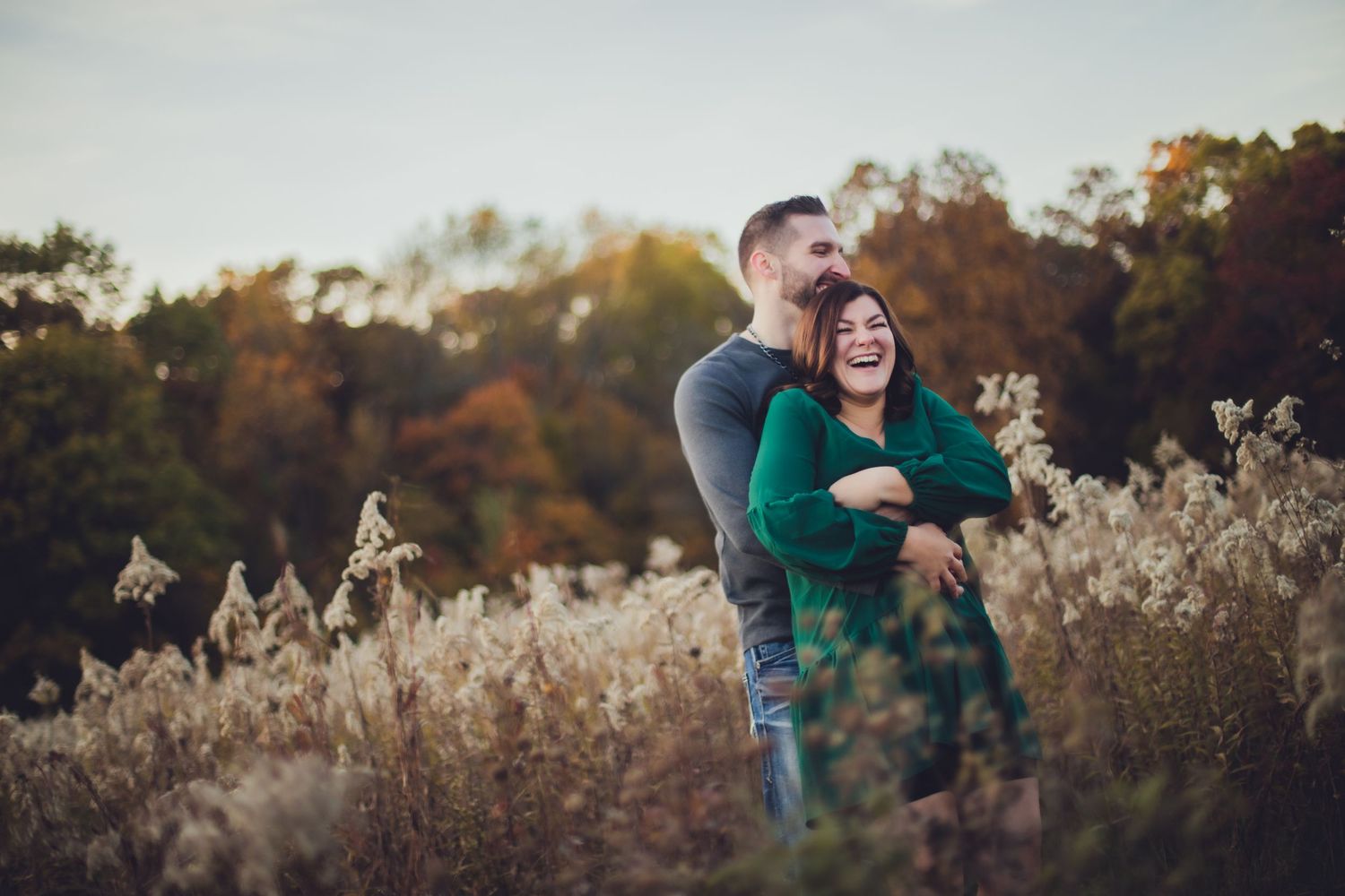 Romantic autumn engagement session in a field with natural golden lighting.