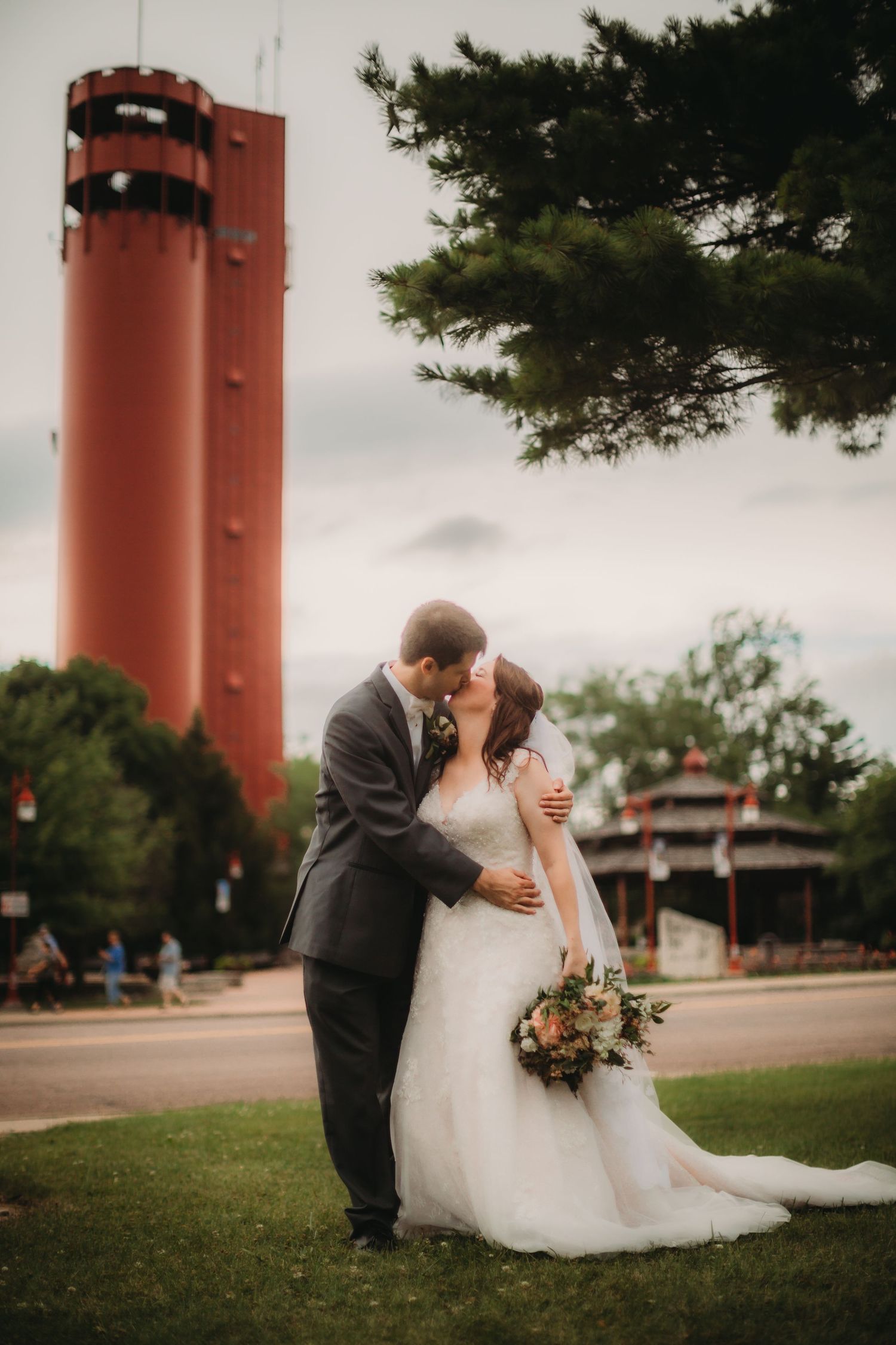 Elegant wedding portrait with couple embracing against backdrop of tall red structure.