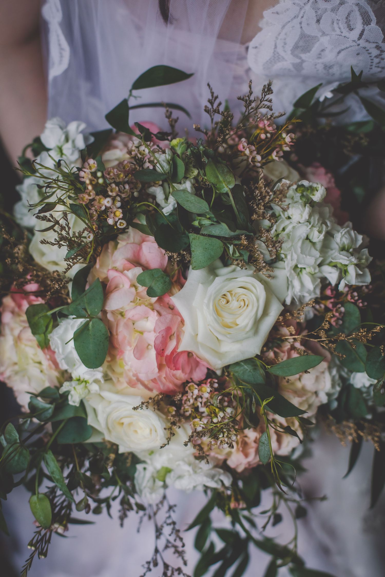 Romantic wedding bouquet featuring pink and white roses with eucalyptus leaves and delicate foliage.