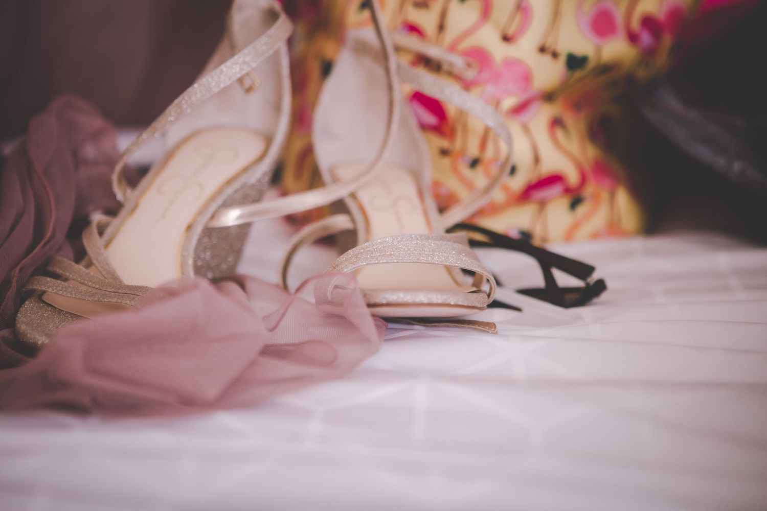 Wedding accessories and shoes arranged on pink fabric.