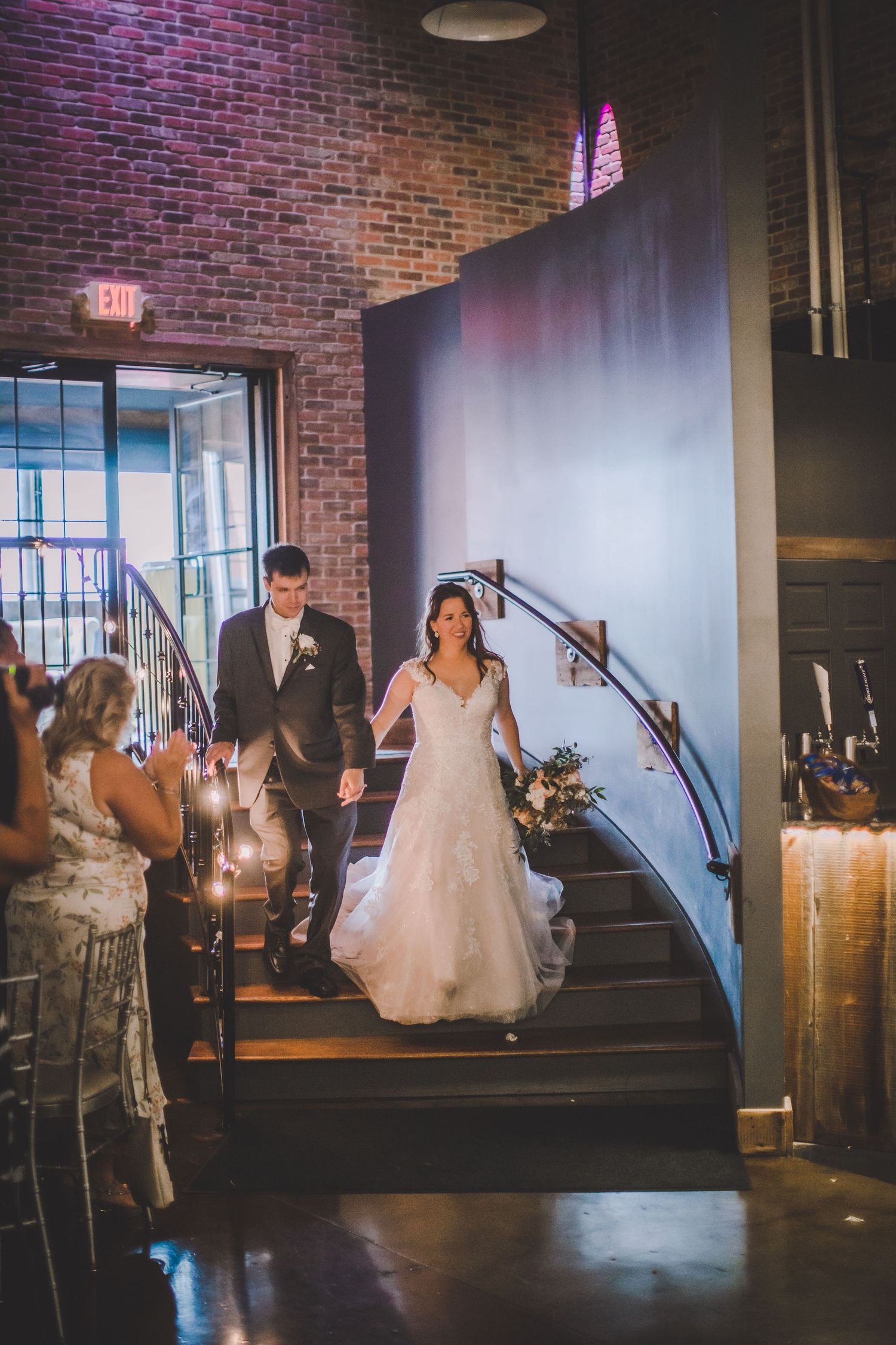 Wedding celebration captured in sequence as couple makes entrance at brick-walled reception venue.
