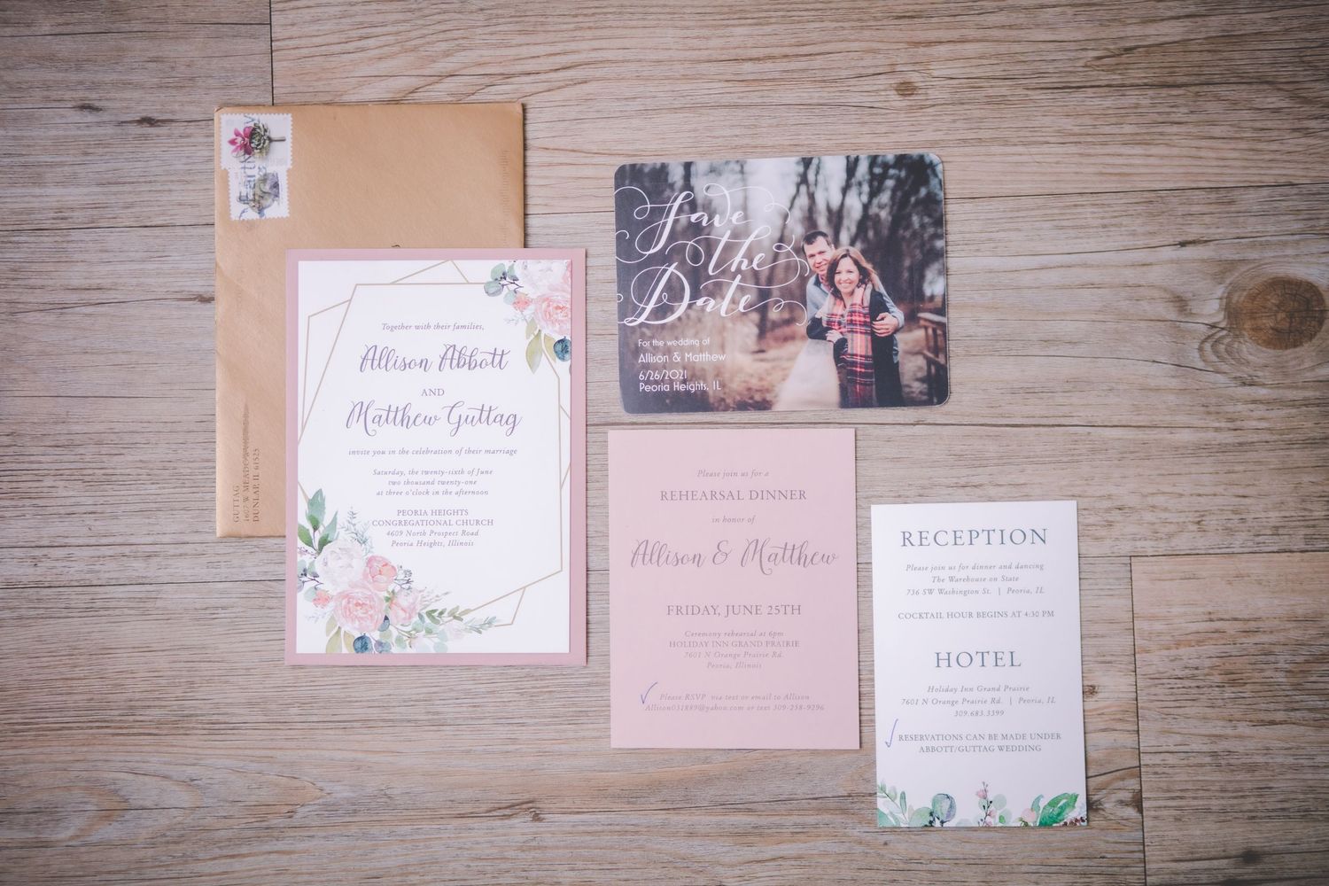 Wedding invitations and stationery laid out on rustic wooden surface.