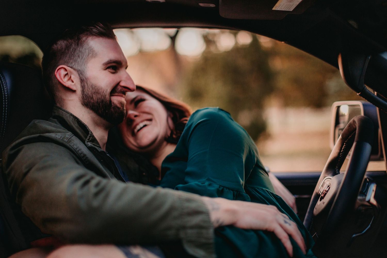 Candid moment of laughter shared between couple inside car during intimate photoshoot.