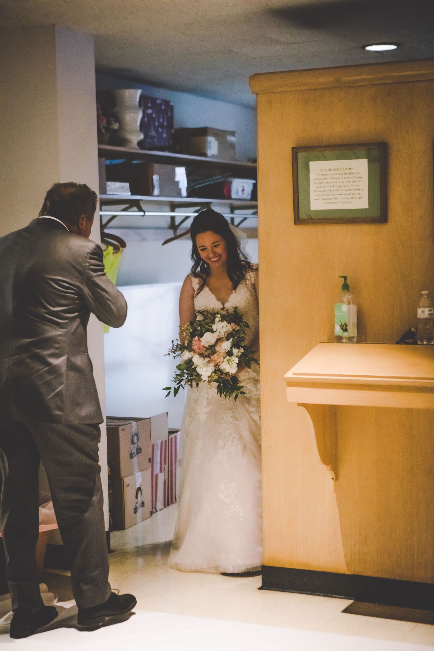Wedding party getting ready in a church hallway with yellow walls.