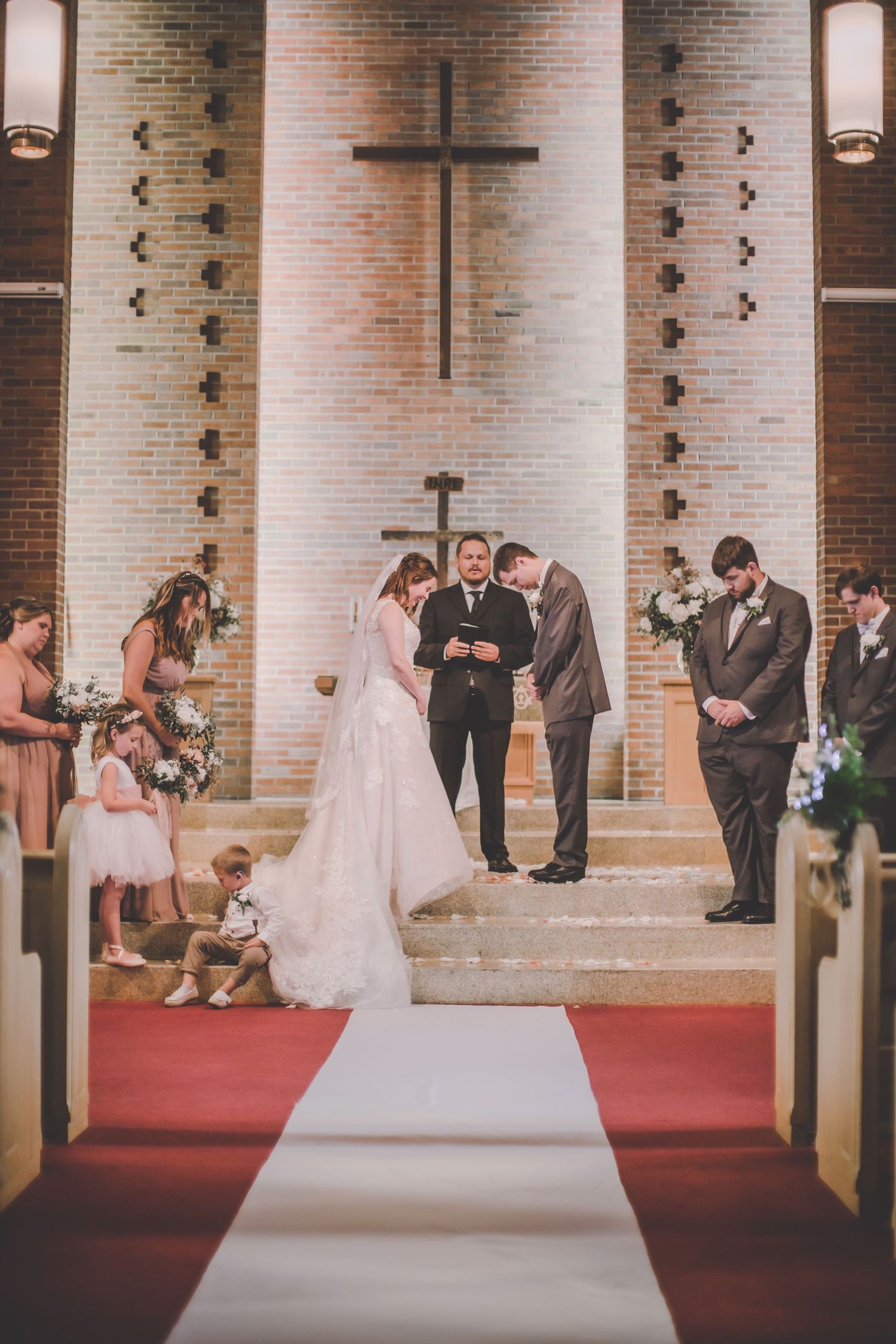 Traditional church wedding ceremony with brick columns and red carpet aisle.
