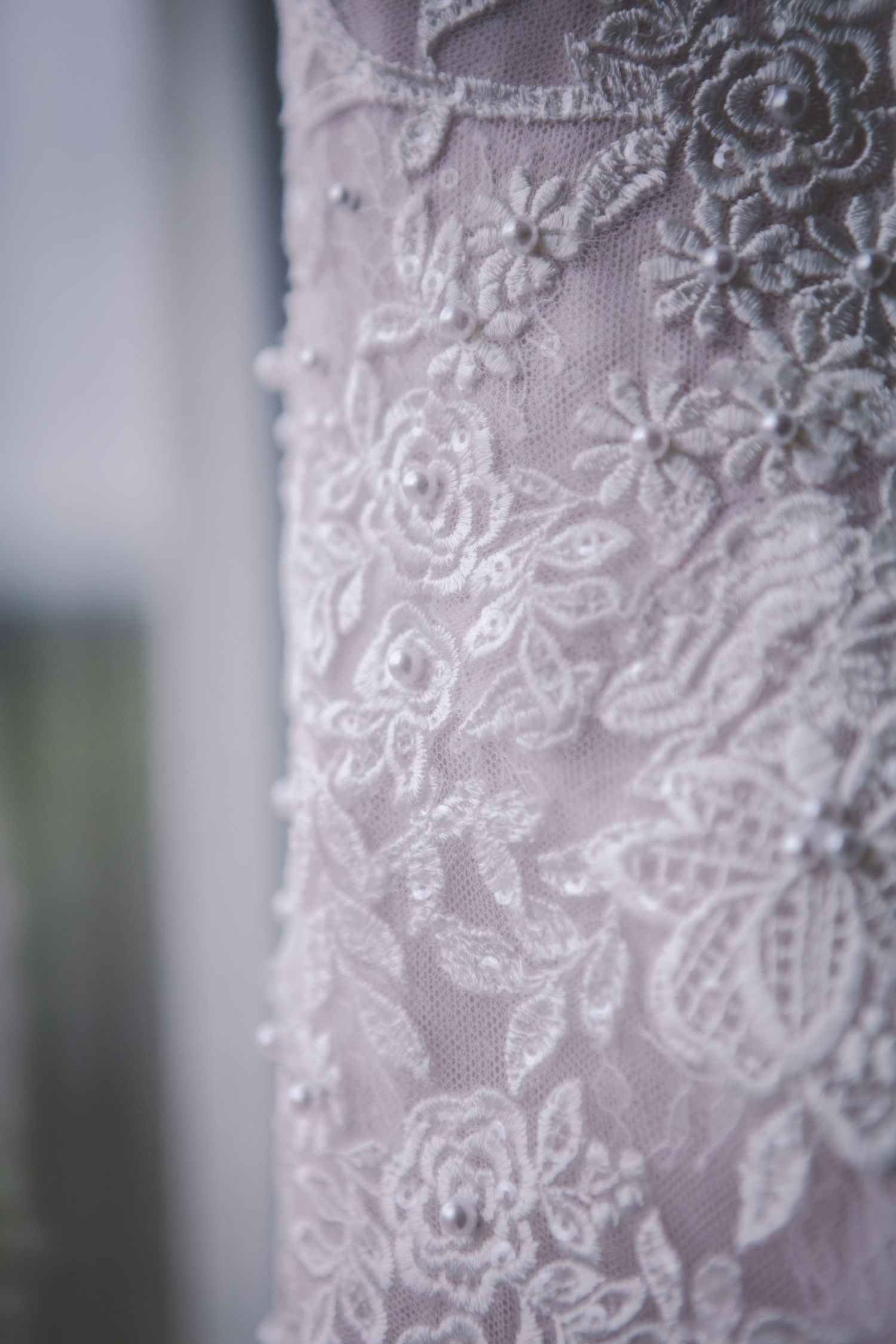 Intricate floral lace pattern detail on white wedding dress fabric.