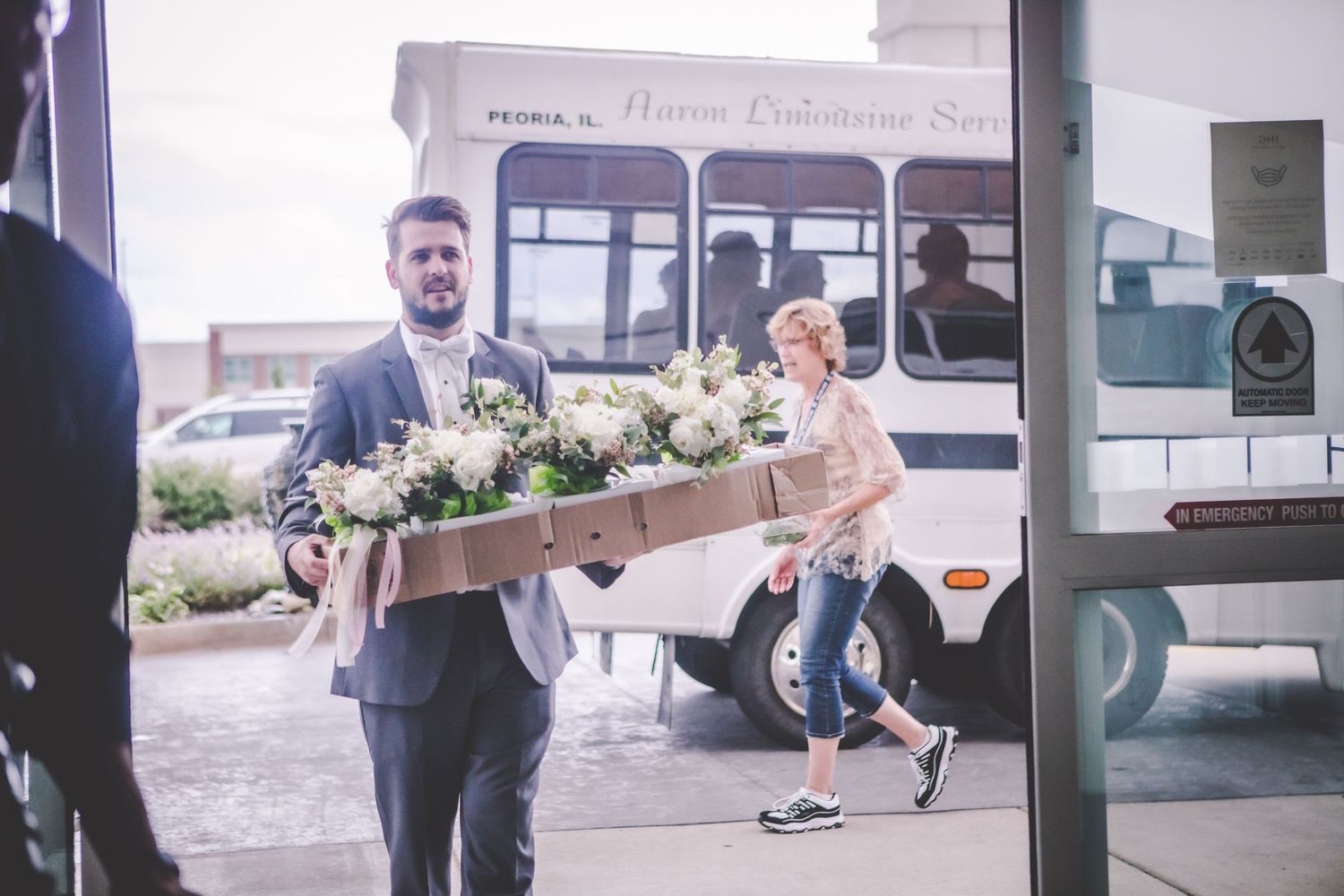 Wedding party members walking and gathering outside a building entrance.