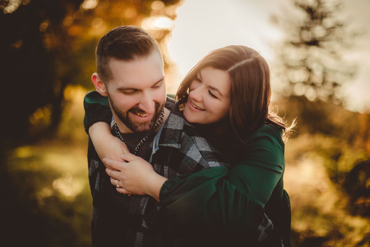 Romantic couple laughing together during a golden hour photoshoot outdoors.