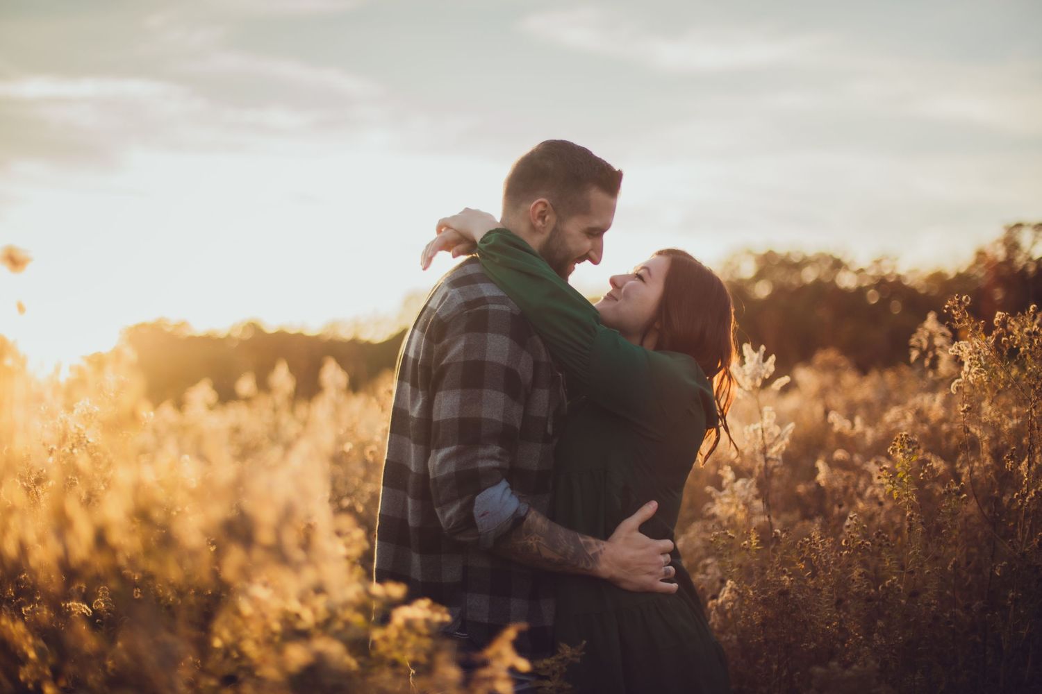 A romantic golden hour moment between a couple in a field of tall dried grass.