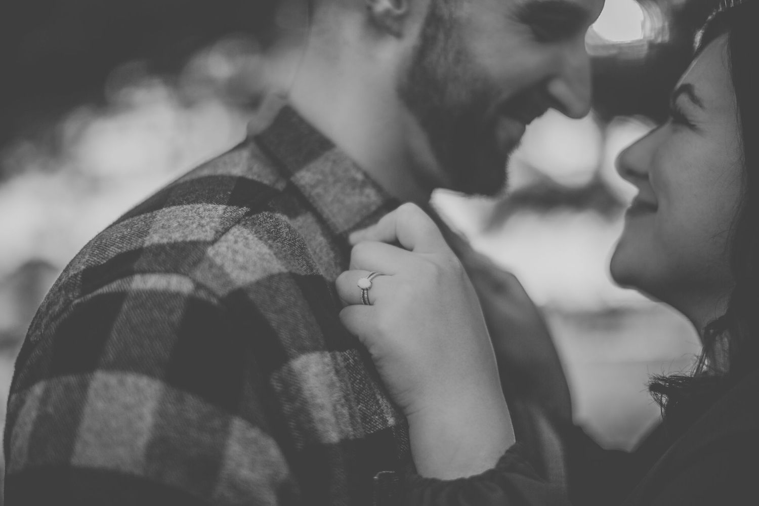 Black and white romantic portrait of couple sharing intimate moment outdoors.