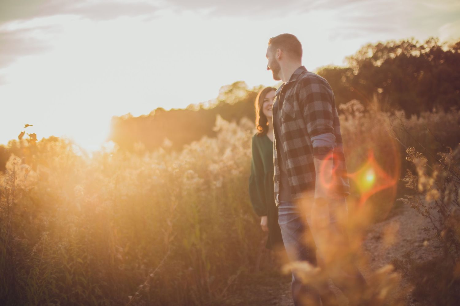 Silhouetted figures stand in a sun-drenched field during golden hour.