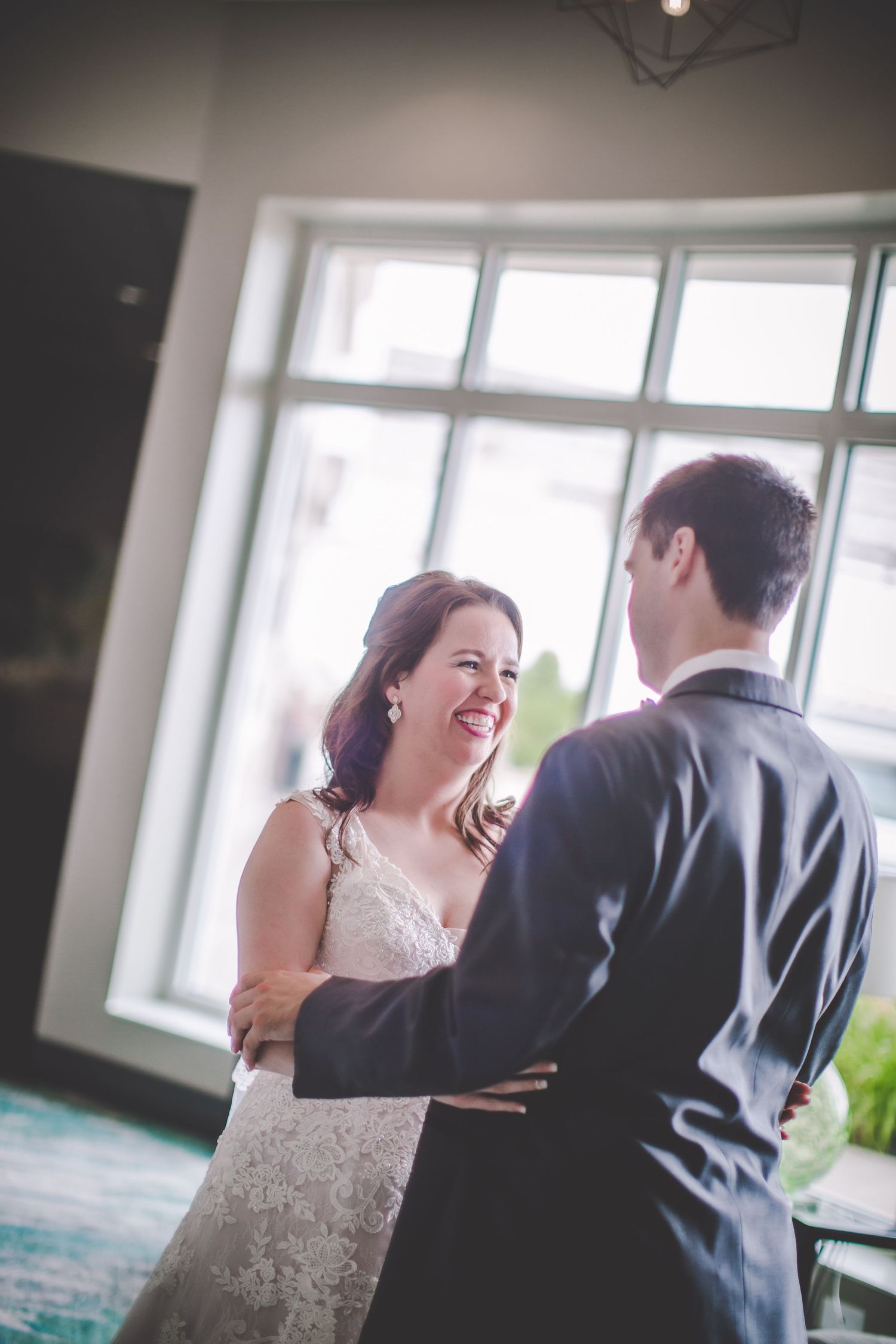 A heartwarming exchange between newlyweds by a bright window during their wedding day.