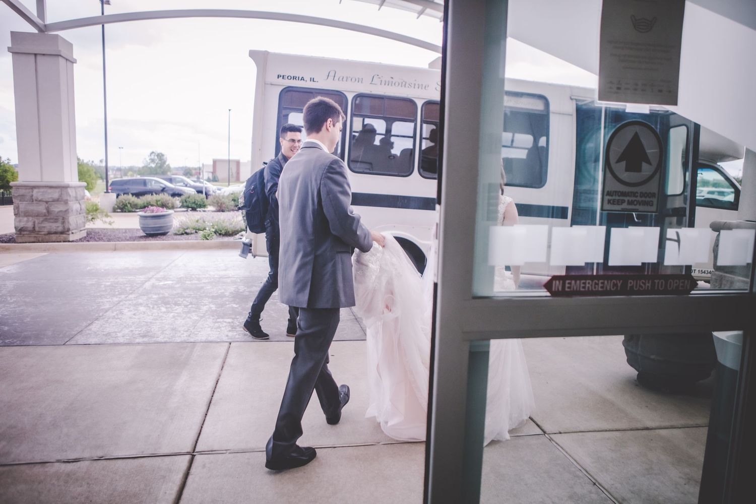People walking under a covered outdoor walkway near parked vehicles.