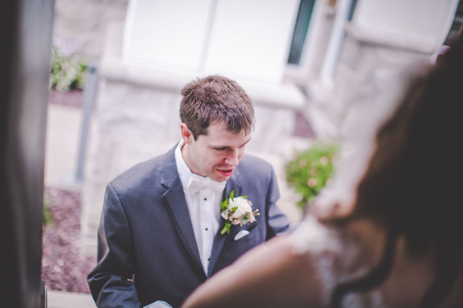 Close up of person in navy suit with boutonniere during wedding ceremony.