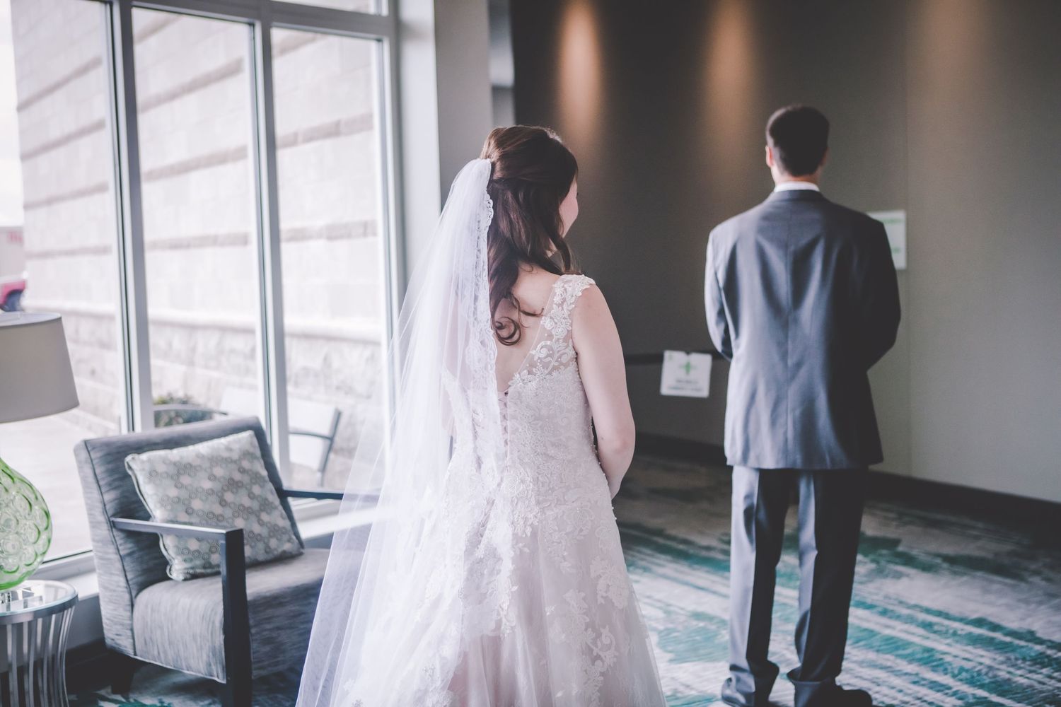 Wedding first look moment captured in a modern room with large windows.