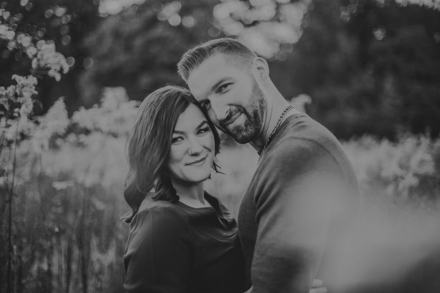Black and white portrait of couple smiling together in natural setting.