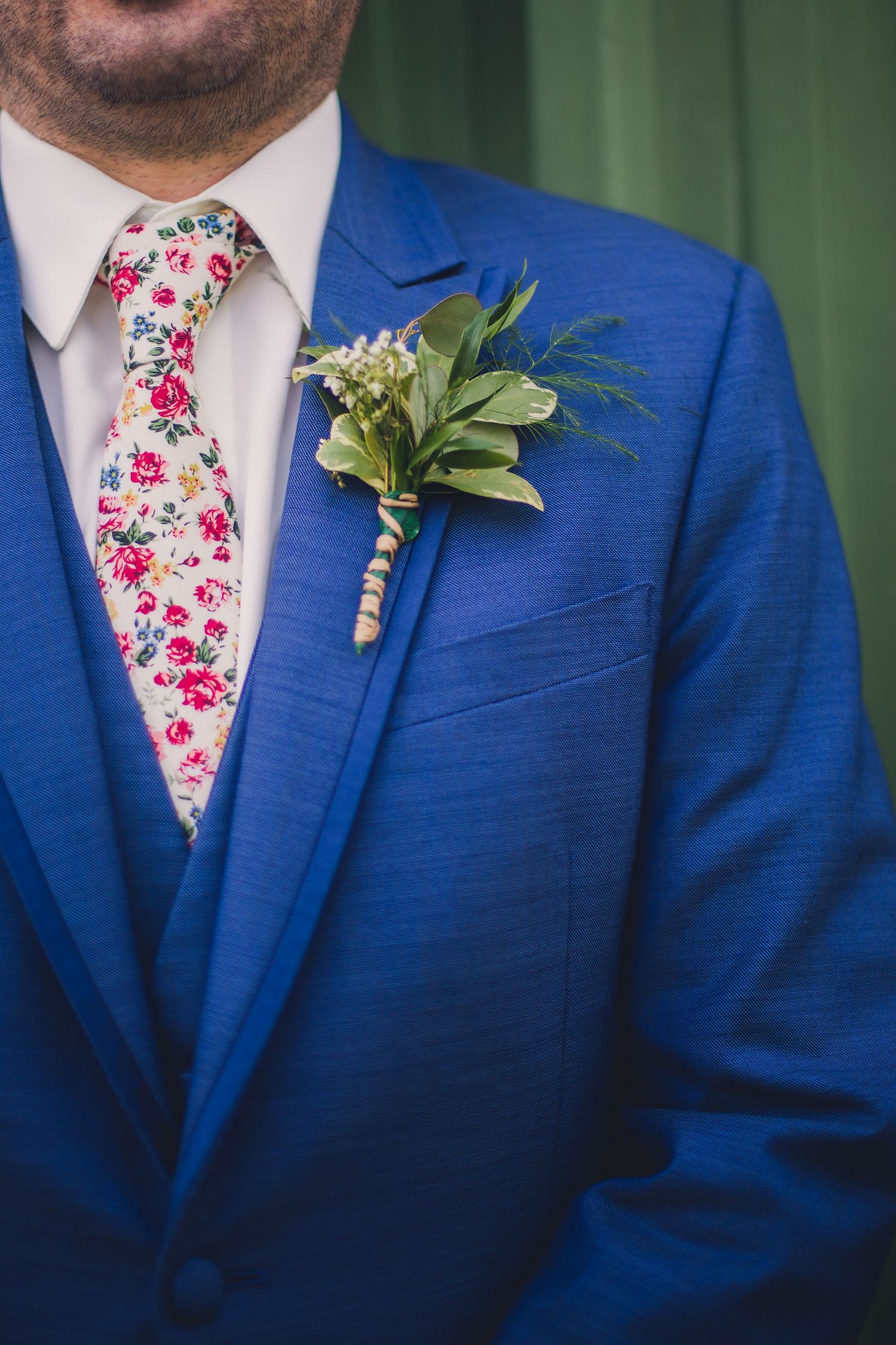Close-up of groomsmen wearing blue suits with floral pink ties and boutonnieres.