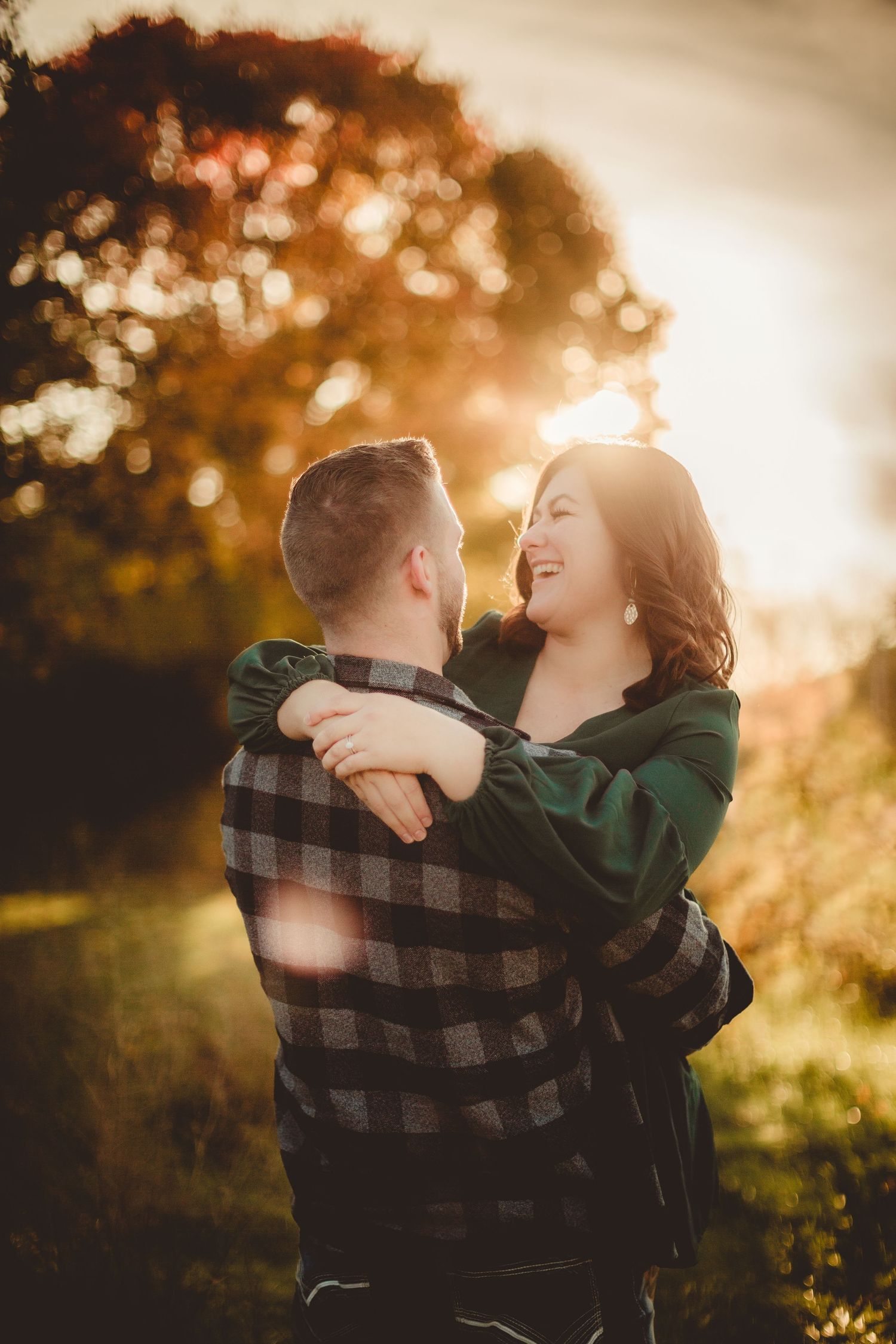 A couple embraces against warm autumn sunlight in a romantic outdoor setting.