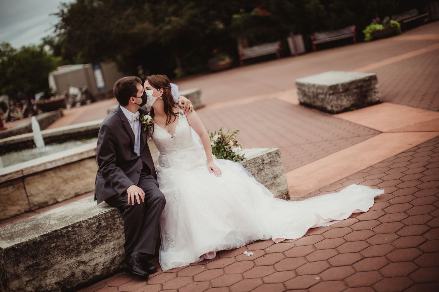 Wedding couple poses for romantic portraits on outdoor brick pathway.