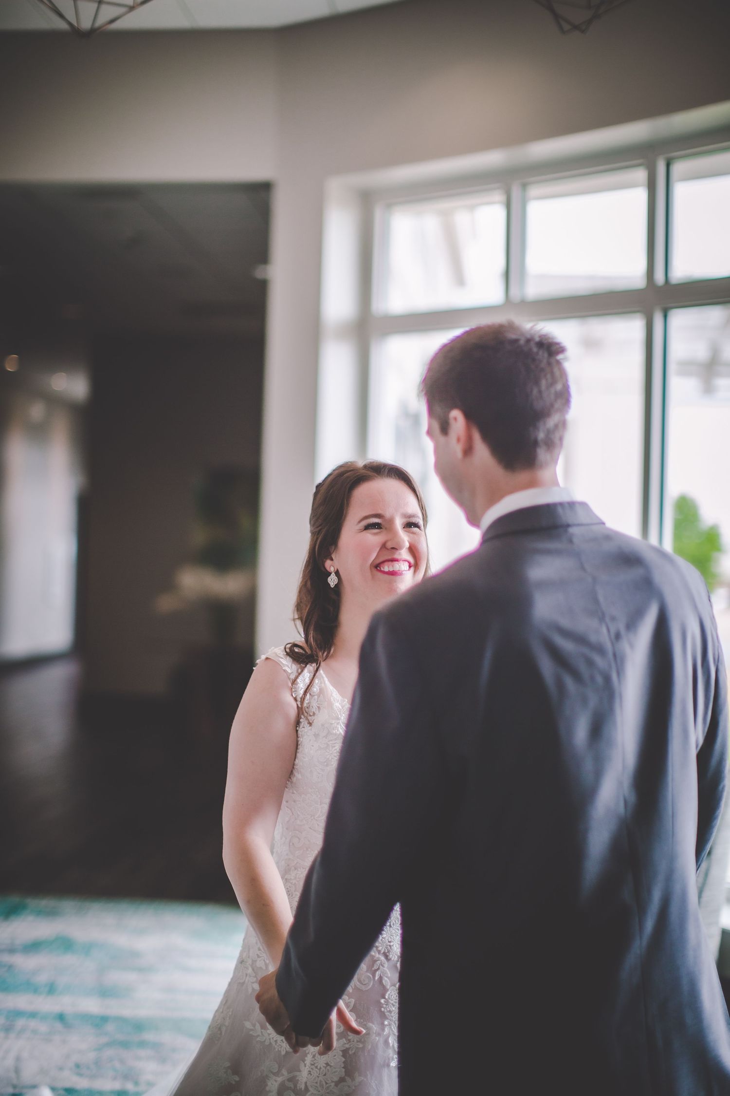 Wedding first look photos showing natural reactions and emotions by large windows.