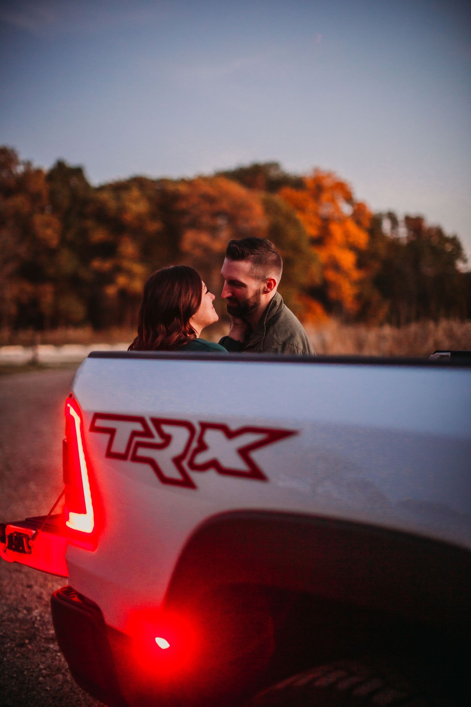 Ram TRX pickup truck tailgate with fall foliage and red taillights glowing.