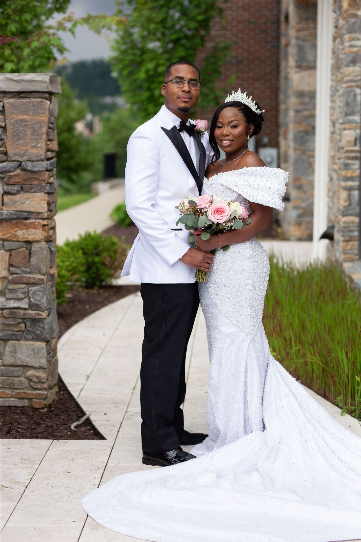 Wedding couple sharing intimate moment on stone pathway with flowing white dress.