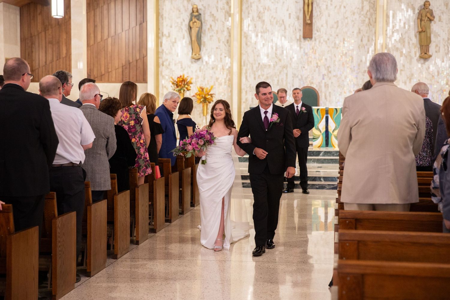 Wedding party and guests gathered in church pews during ceremony.