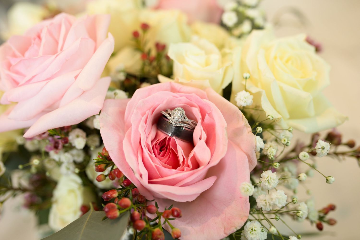 Delicate pink and cream roses arranged with greenery for wedding decor.