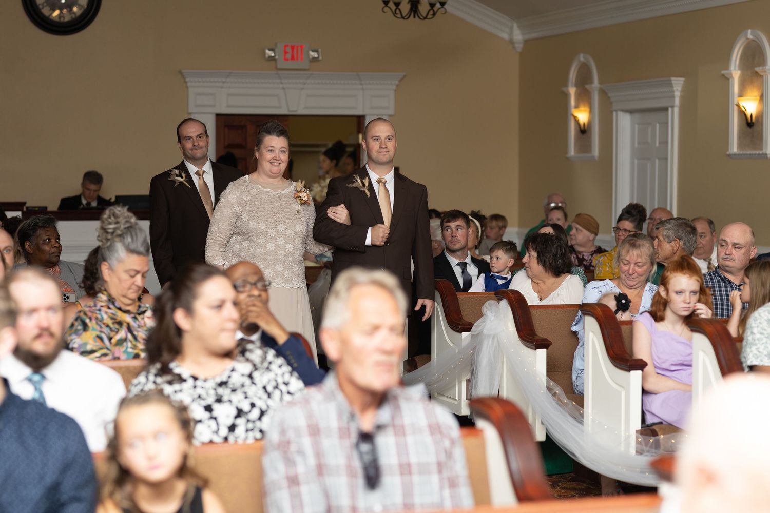 Wedding reception hall filled with guests seated in rows of white chairs.