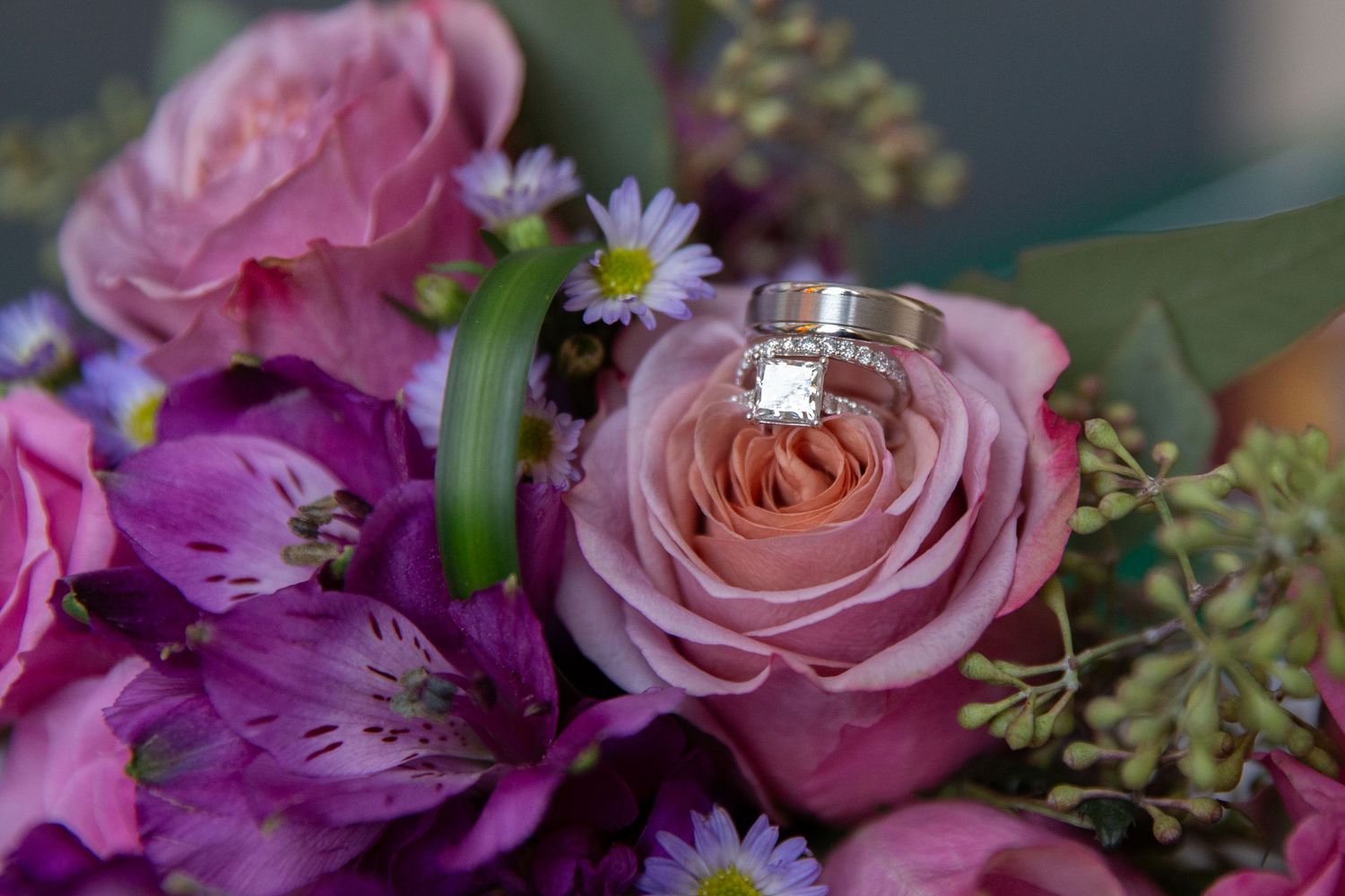 Elegant pink and purple floral wedding arrangements with roses and mixed flowers.